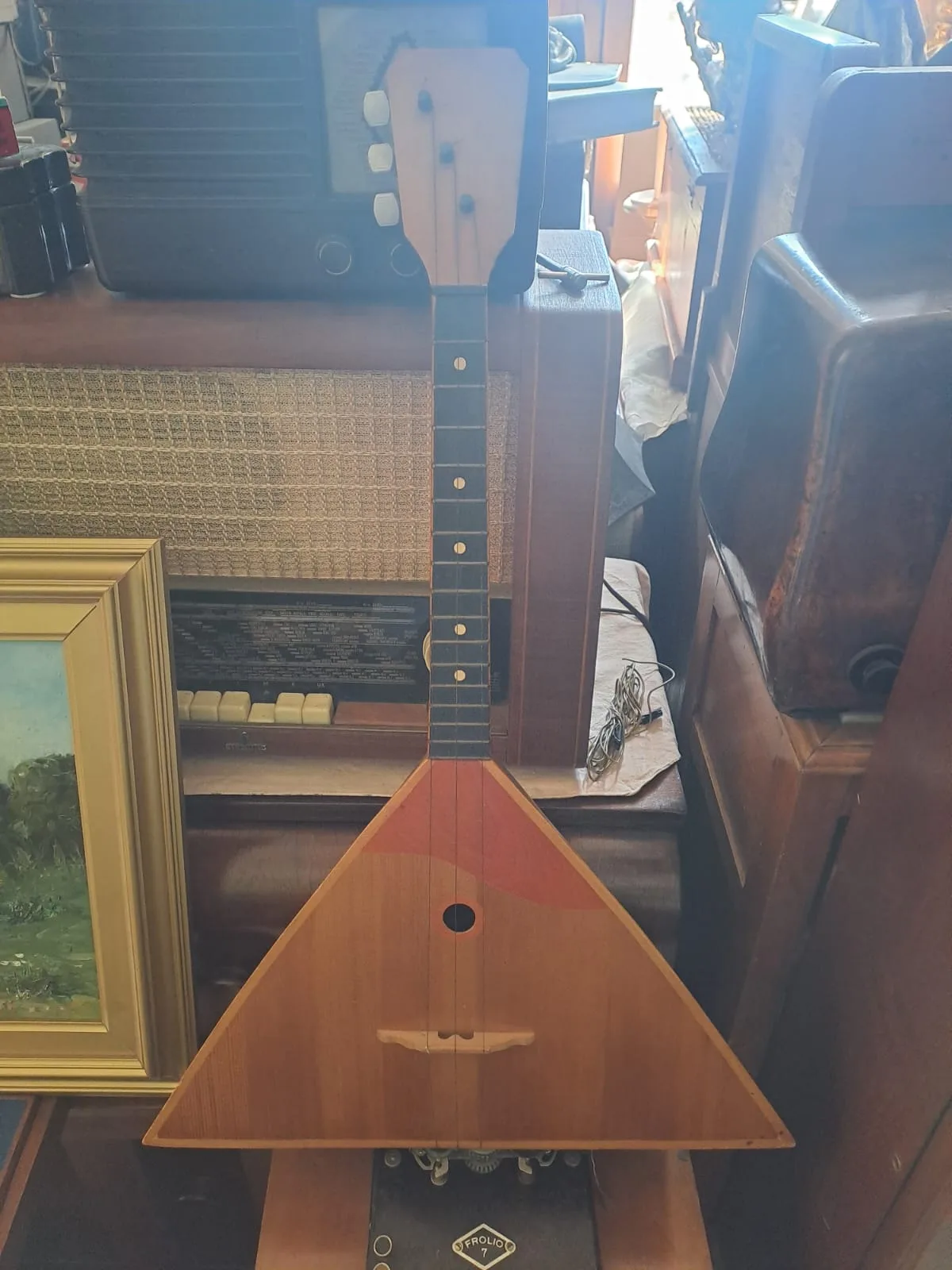Balalaika triangolare in legno chiaro appoggiata a un mobile
